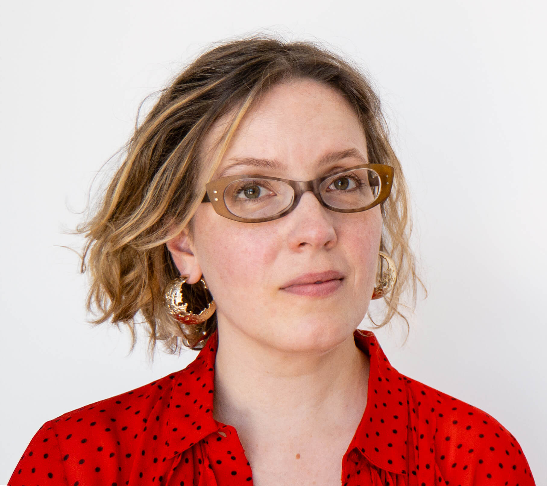 Alexandria Lawrence, Founder of ALSO in PINK. Portrait Wearing A Ganni Red Blouse And Gold Earrings By Annelise Michelson