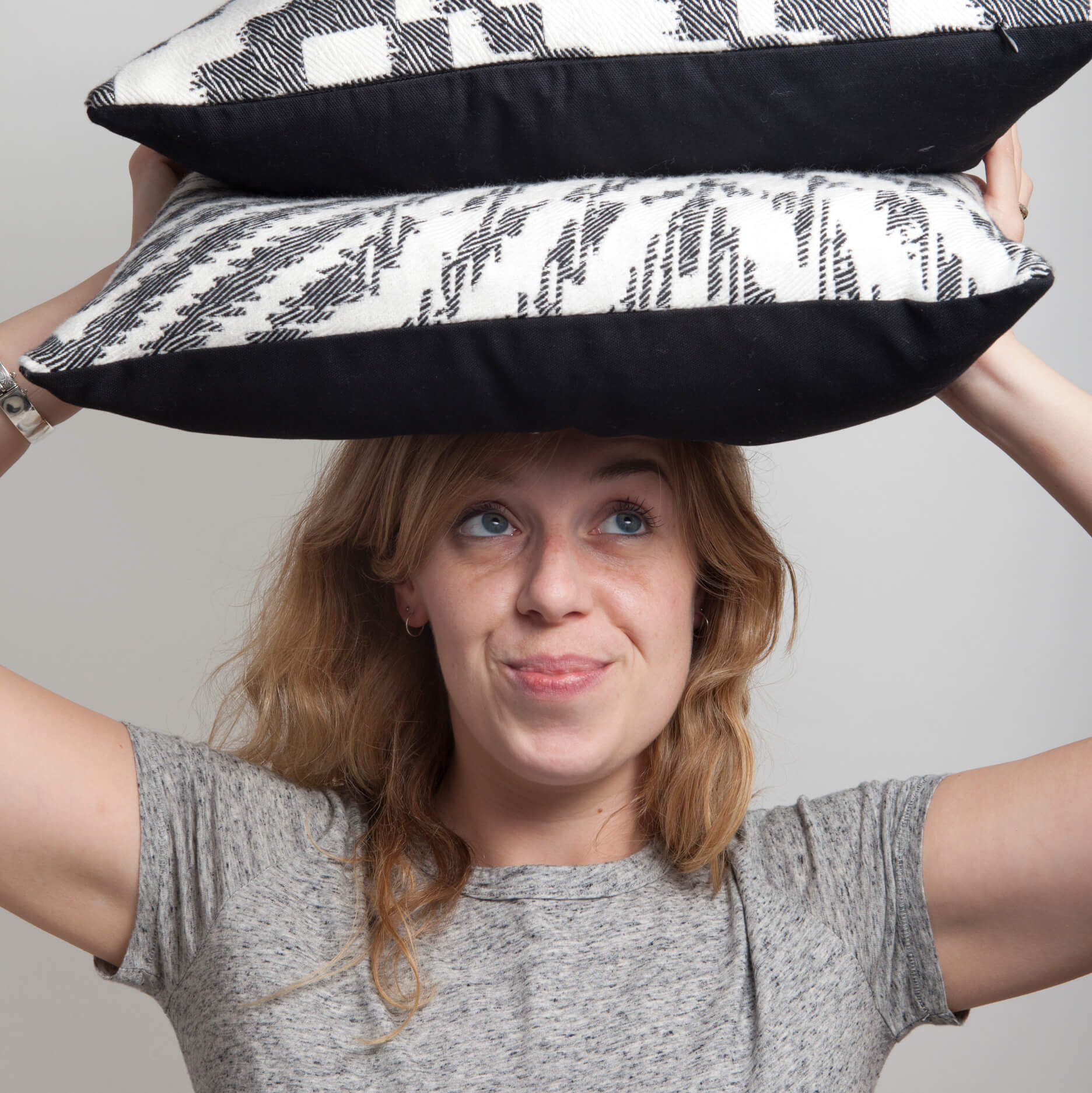 Textile Designer Beatrice Larkin Holding A Couple Of Her Bold Monochrome Cushions Above Her Head