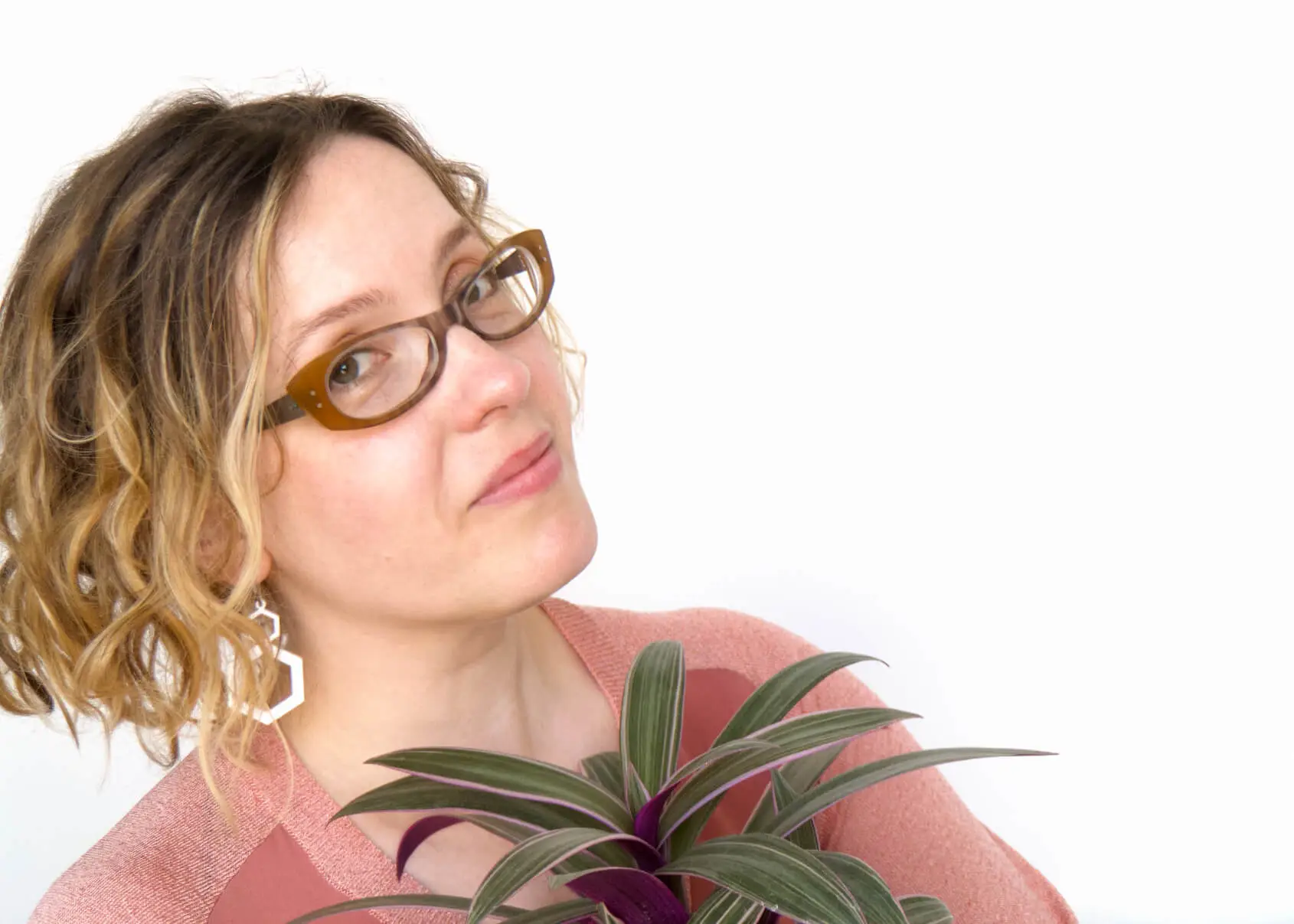 Portrait of Alexandria Lawrence wearing a dusty pink top and holding a pinky purple plant.